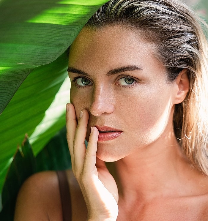 Woman posing with green leaves background.