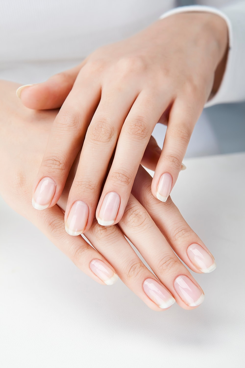 Well-manicured hands with natural nail polish.