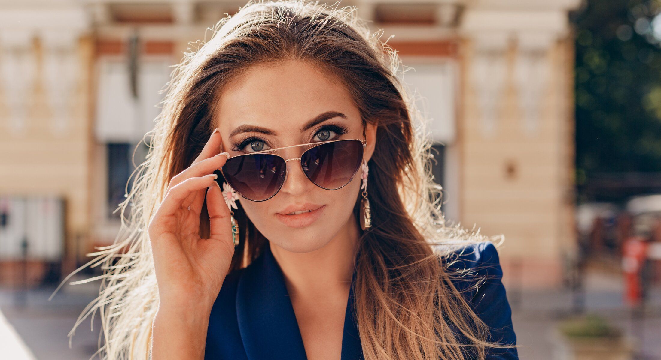 Woman with sunglasses and glamorous jewelry outdoors.