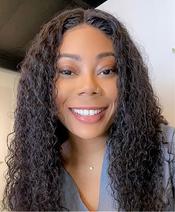 Smiling woman with curly hair in casual attire.